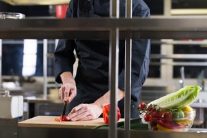 Chef picando vegetales en una tabla, simbolizando los casos de éxito de dark kitchens en Latinoamérica.
