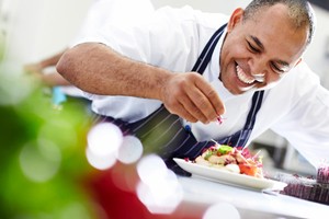 Chef decorando un plato gourmet, representando diferentes tipos de catering en eventos.