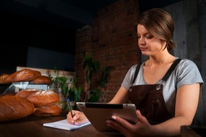 Mujer panadera usando una tablet para ajustar precios dinámicos según la demanda y disponibilidad de productos.