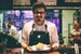 Fotografía de un chef sonriendo y mostrando un plato.