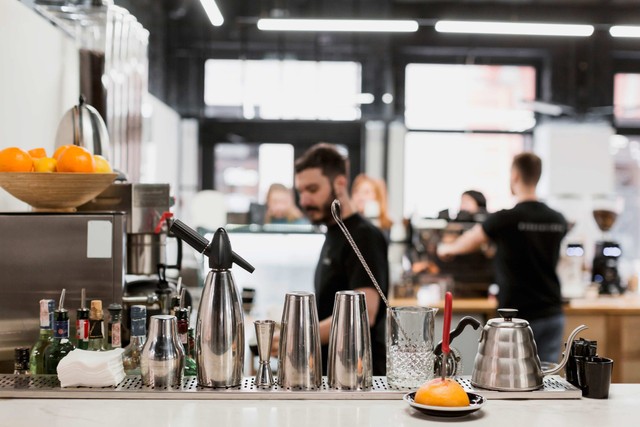 ¿Qué tan rentable es una cocina oculta?: mostrador moderno de una coctelería, con vasos en el mostrador, una escena borrosa en el fondo con un joven