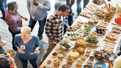 Esta imagen muestra una escena vibrante y dinámica de un evento social o convivencia laboral con un enfoque en la gastronomía.