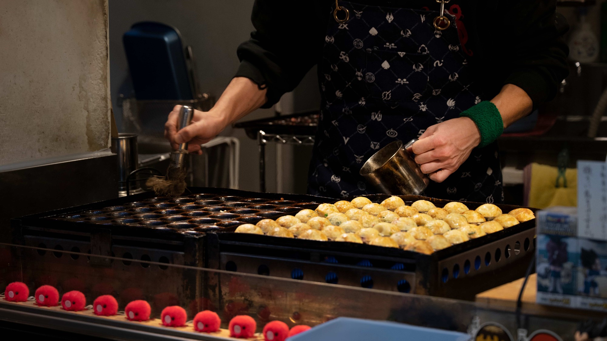 comidas de restaurante: mãos masculinas fritando os takoyakis está vestido com uma bata preta