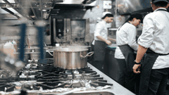 En la imagen se observa una cocina profesional de restaurante en pleno funcionamiento.