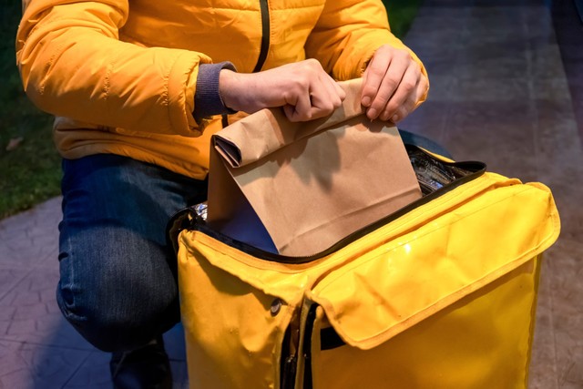 Cuántas cocinas oscuras hay en Chile: repartidor con su mochila amarilla entregando comida lleva una campera amarilla
