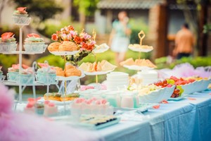 Mesa al aire libre con platos decorativos, frutas y dulces, ilustrando la diferencia entre banquete y catering en un entorno elegante.