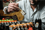 sostenible: hombre de blusa blanca comiendo sushi, urumaki y hossomaki de salmón