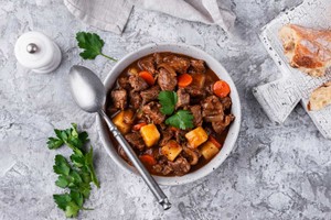 Plato tradicional de estofado de carne con papas y zanahorias, acompañado de pan rústico. Deliciosa comida francesa casera.