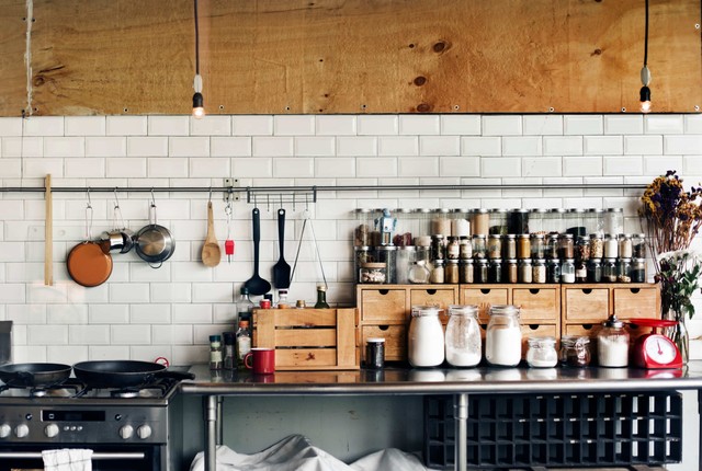 utensilios de cafeteria: Cocina con ollas sobre una encimera, dentro de las ollas hay azúcar y varios cubiertos colgados en la pared.