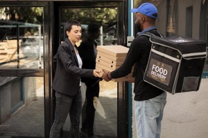 Repartidor entregando cajas de comida a cliente, ilustrando los tiempos de entrega en dark kitchen en zonas residenciales.